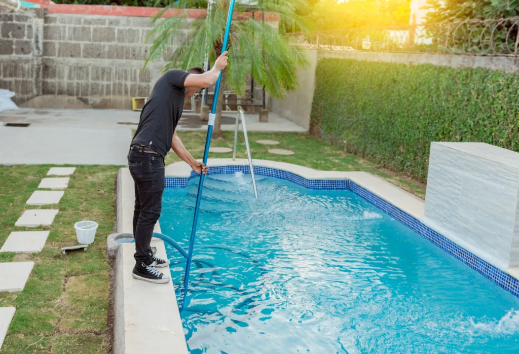 homme nettoyant un petit bassin avec un aspirateur